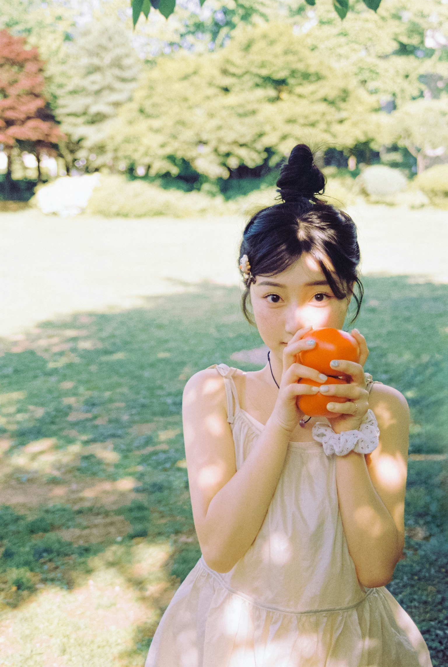 一个女孩在公园里拿着橙子阳光明媚和绿色背景