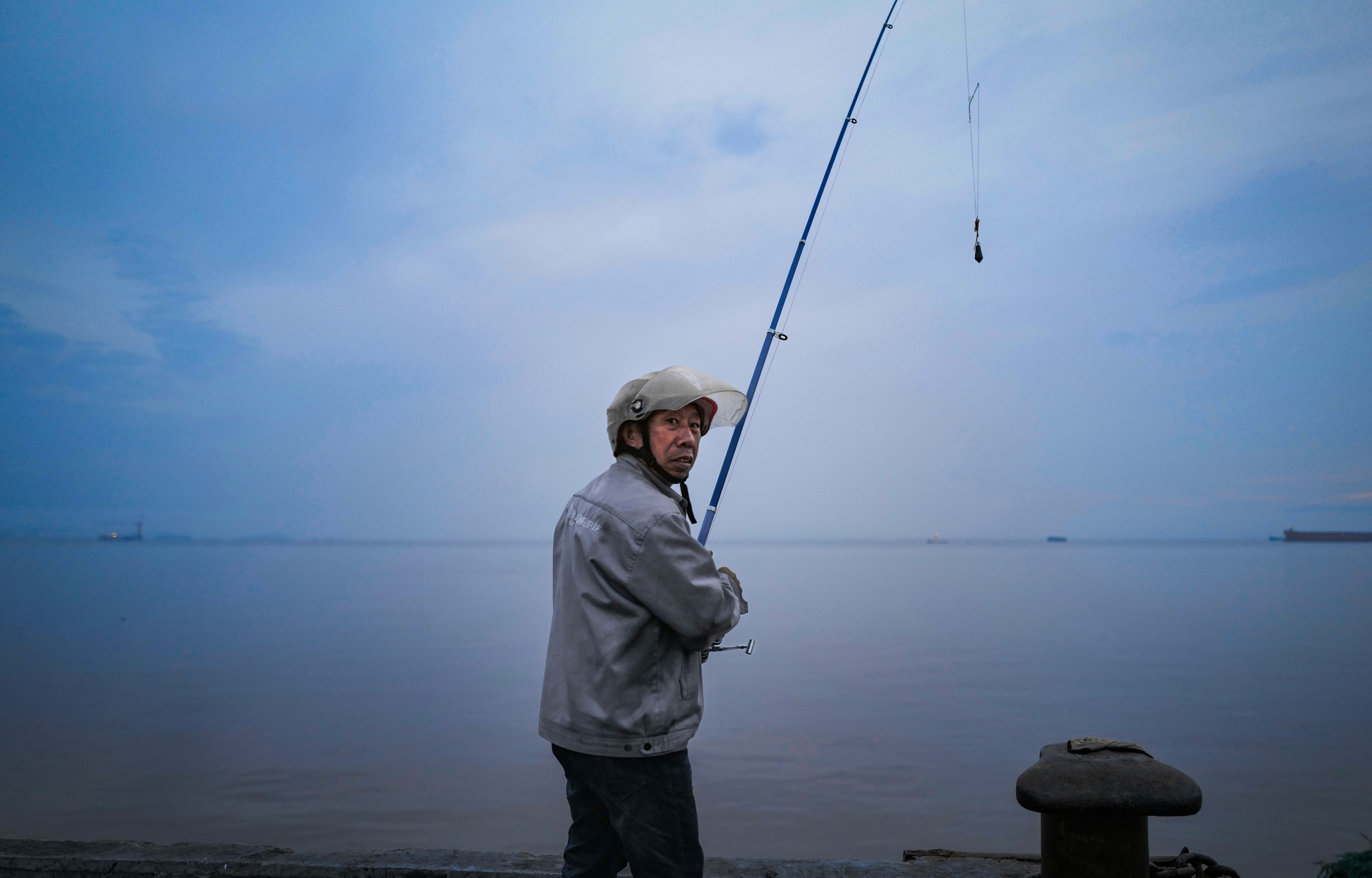 海辺で釣り竿を構える漁師の男性