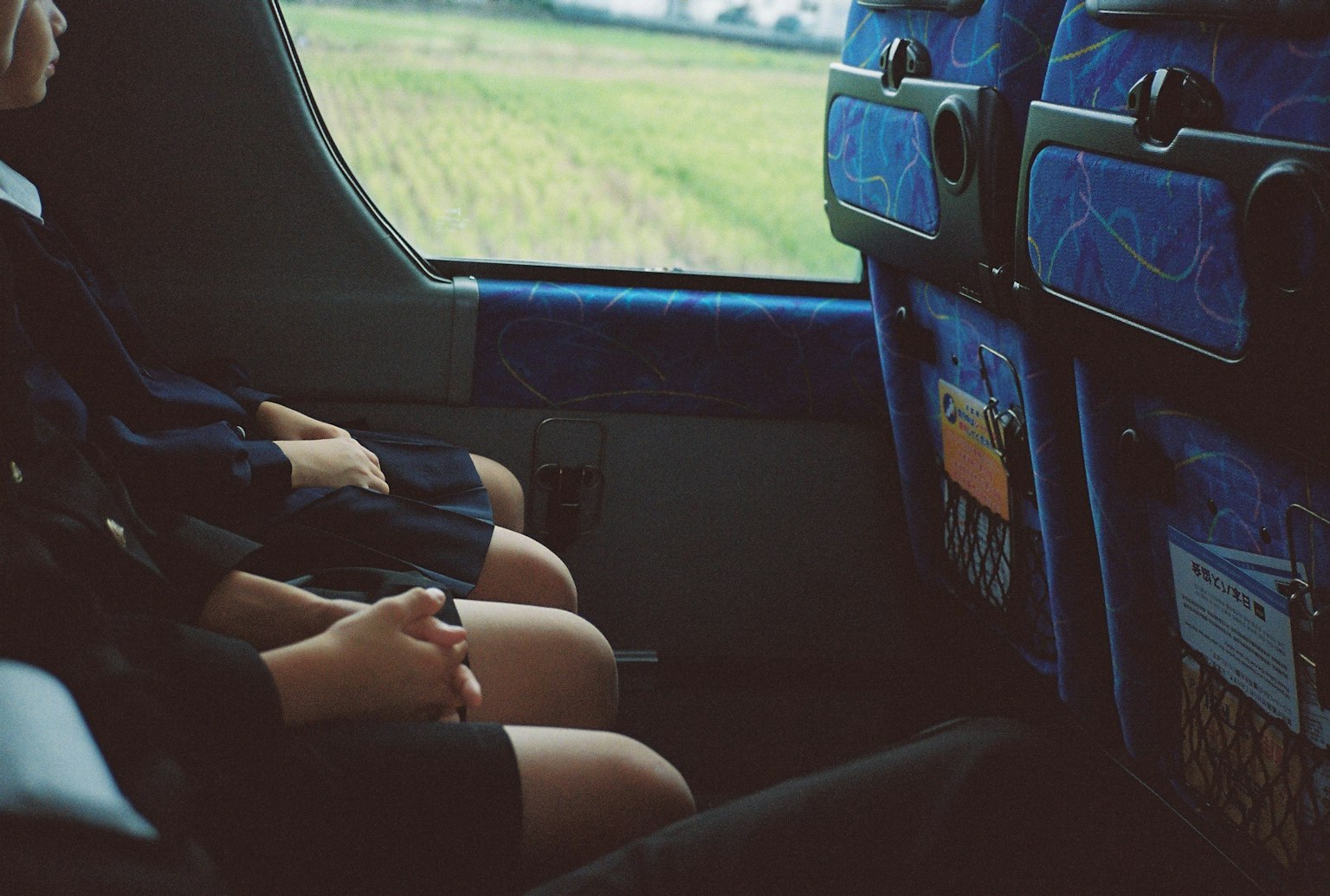 バスの窓から見える風景と座っている子供たちの足