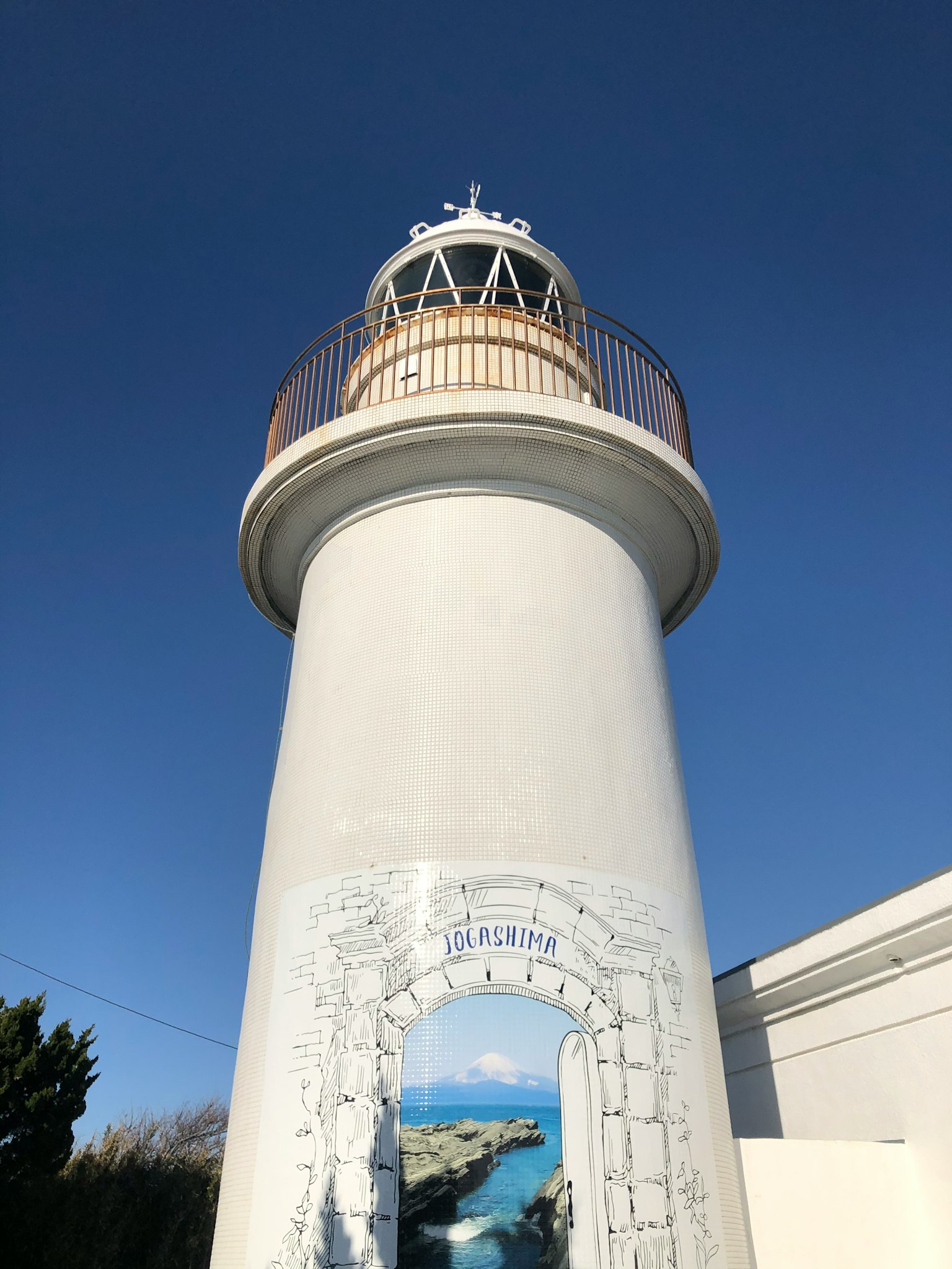 Faro blanco con una plataforma de observación redonda bajo un cielo azul