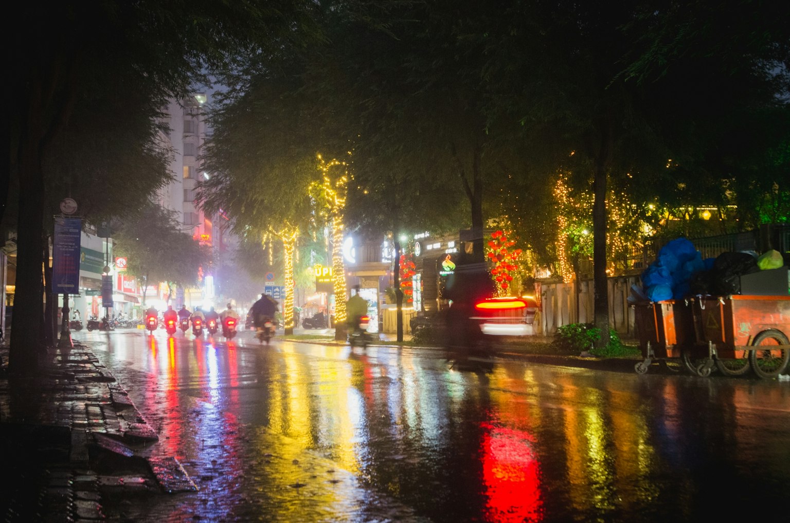 Escena nocturna de la calle con reflejos coloridos en la lluvia