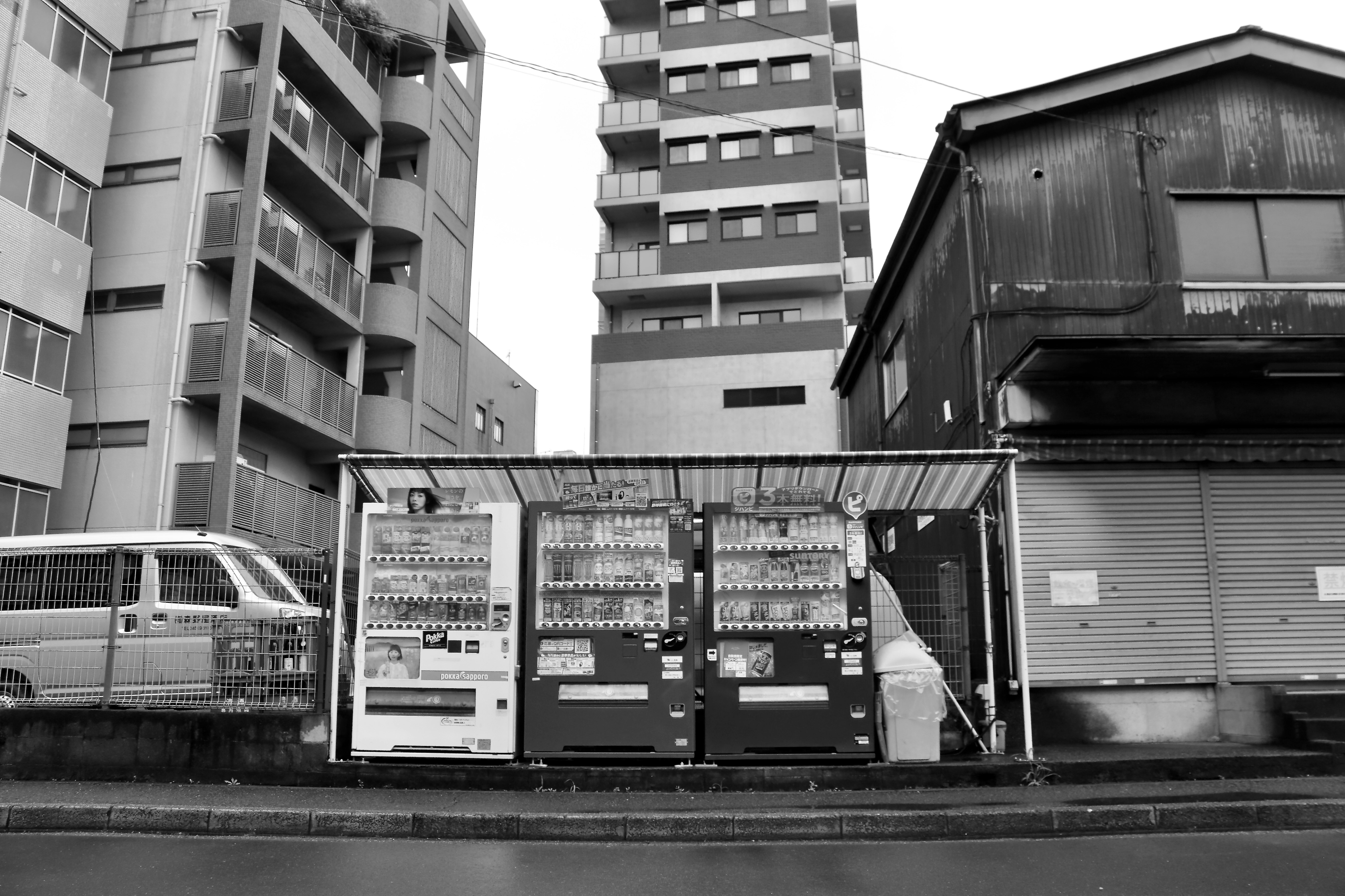 モノクロの高層住宅とフェンス越しの機械設備