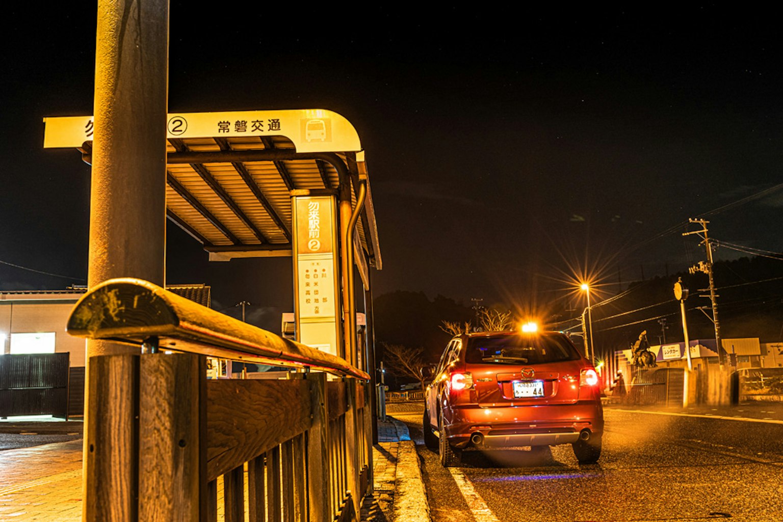 Scène nocturne d'un arrêt de bus avec une voiture rouge