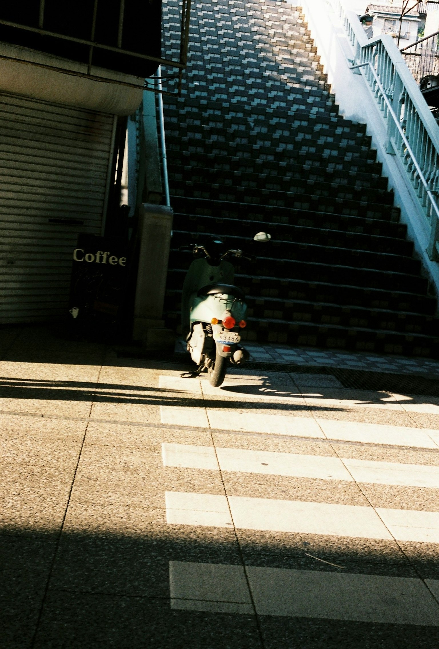 Una motocicleta estacionada frente a escaleras con un fuerte contraste de sombras