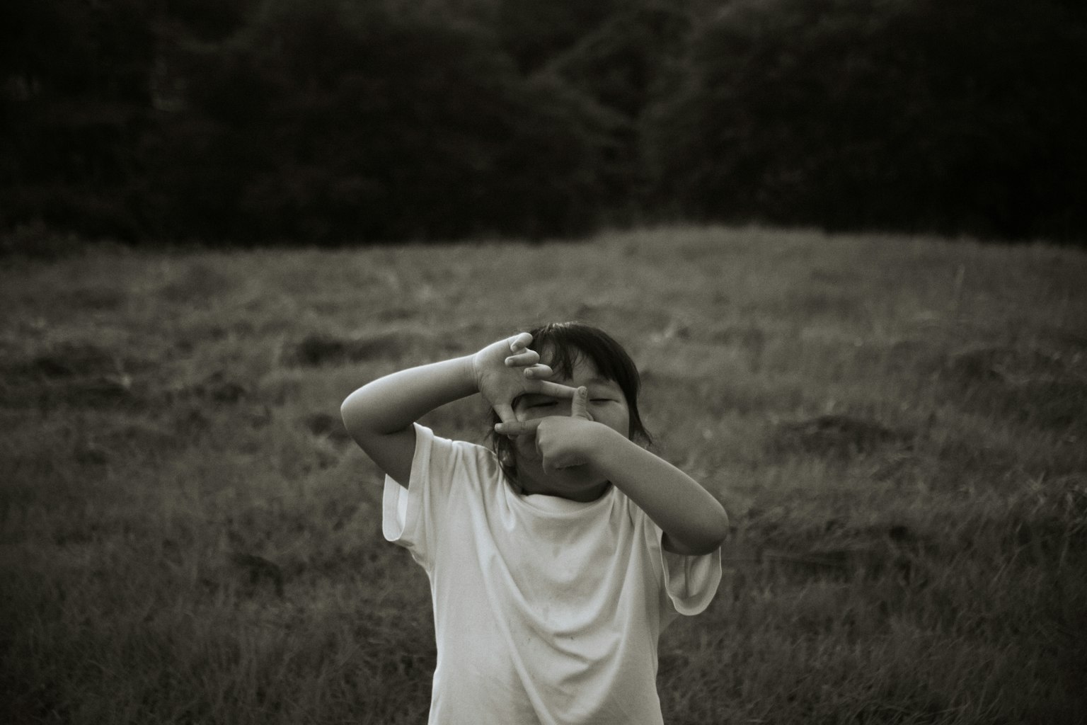 Un niño con una camiseta blanca posando en un campo de hierba