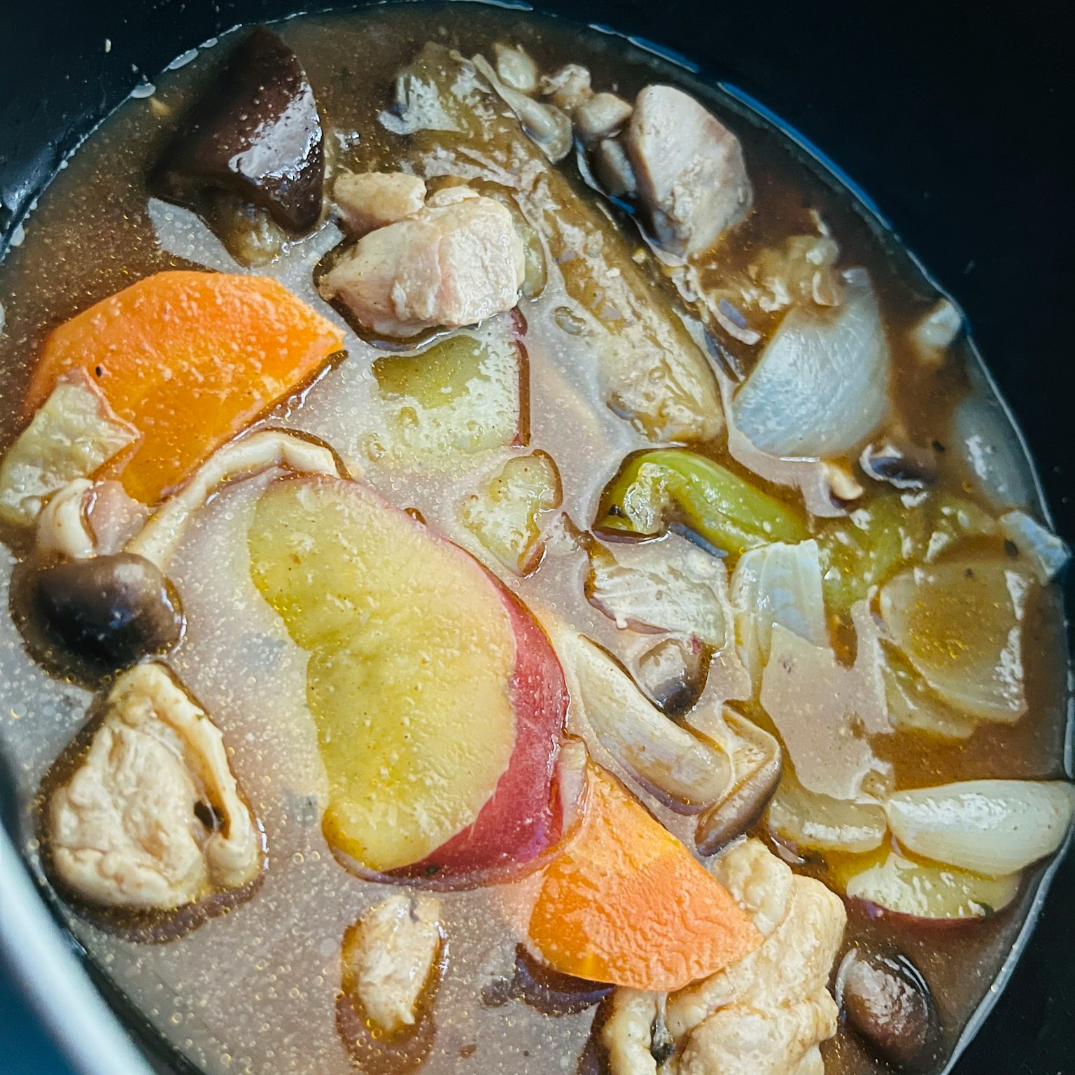 A pot of chicken and vegetable stew featuring colorful vegetables in a warm broth