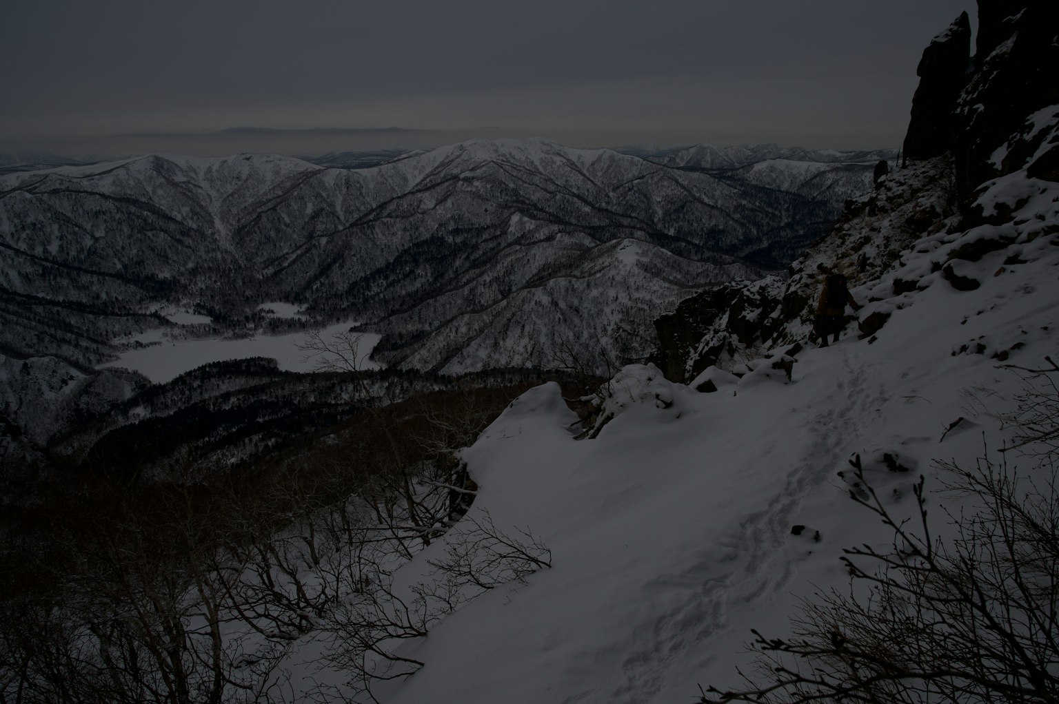 Dramatische Aussicht auf schneebedeckte Berge und Täler unter einem dunklen Himmel