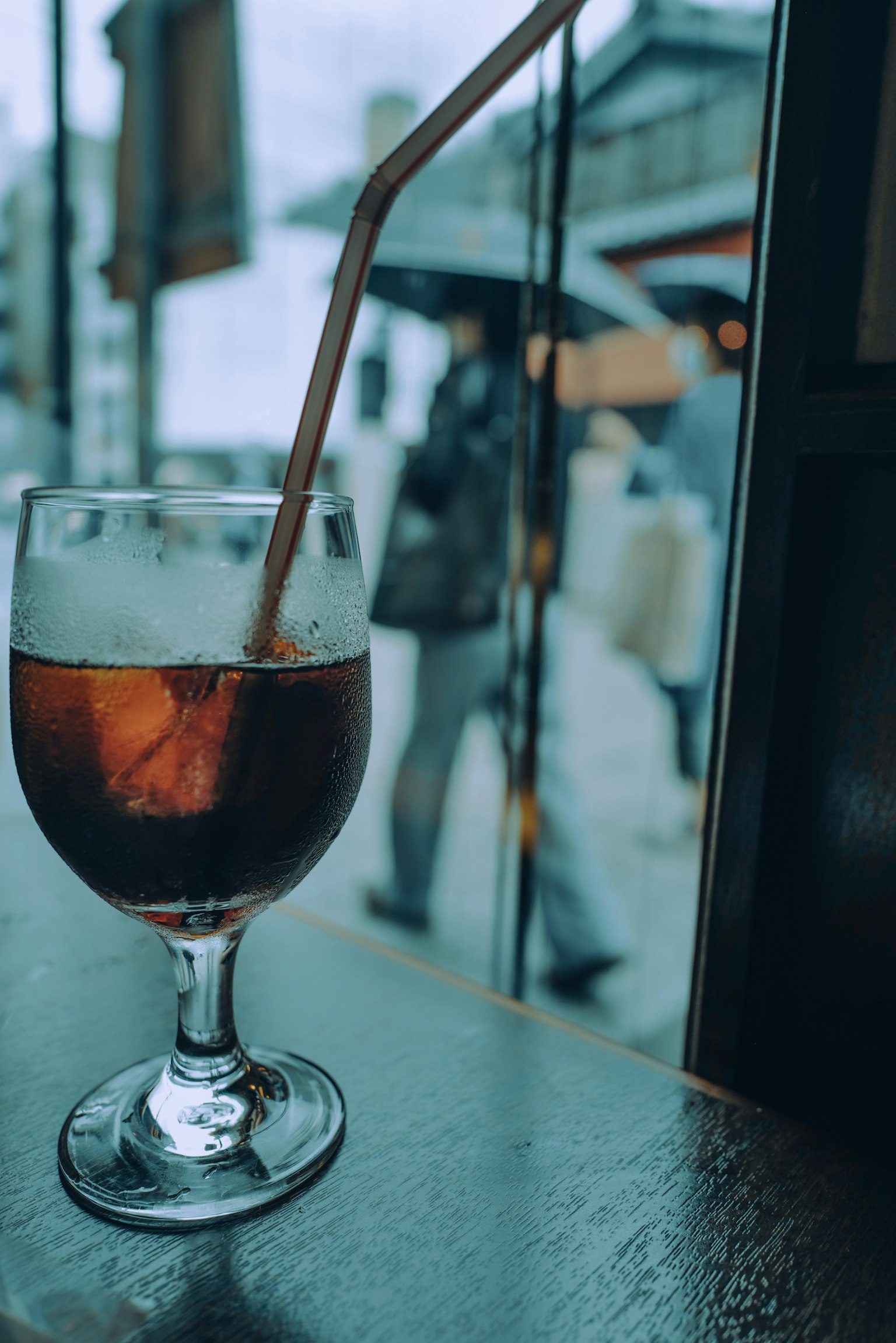 窗台上的冷飲玻璃杯，背景中有行人走過