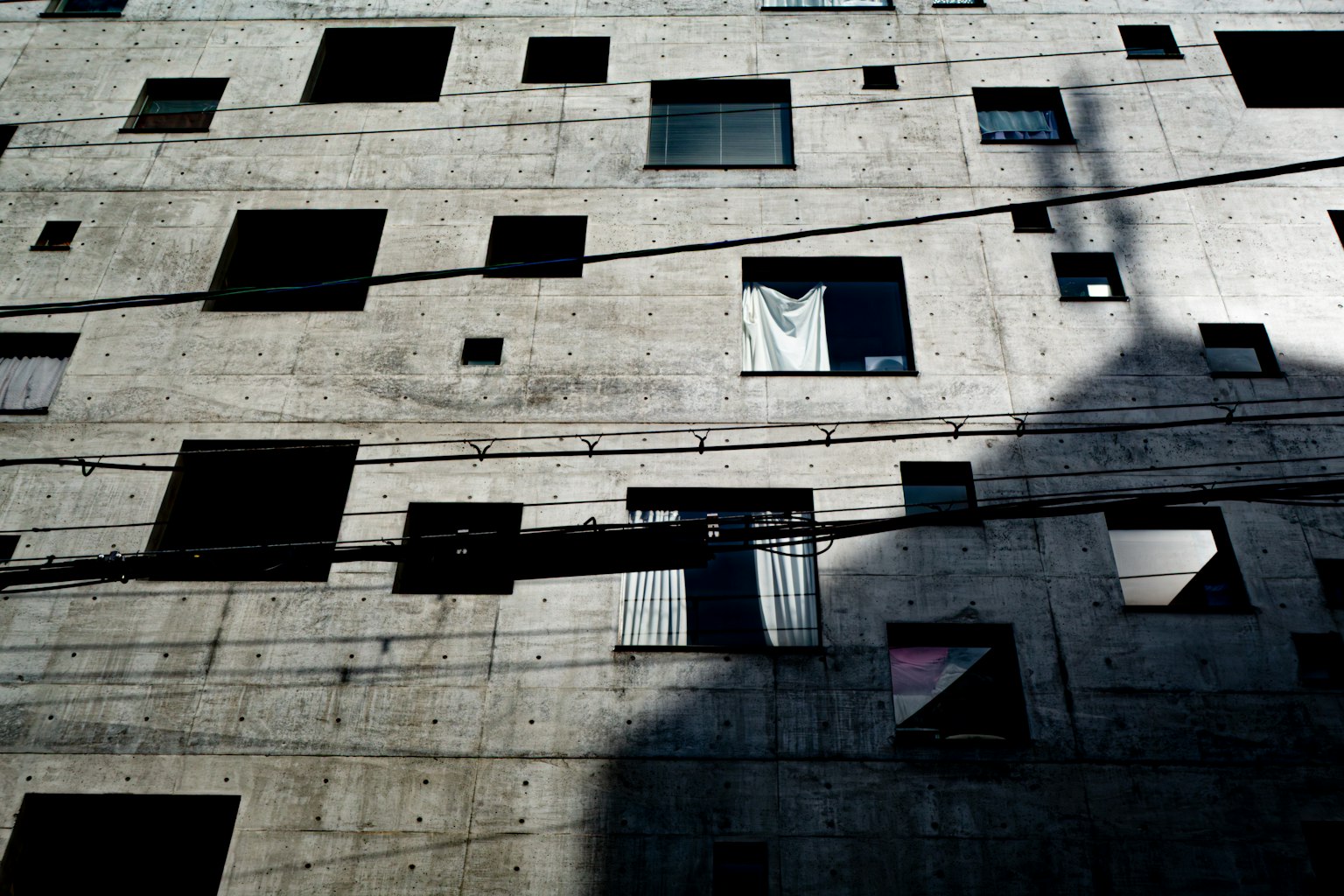 Esterno di un edificio con finestre disposte irregolarmente su un muro di cemento