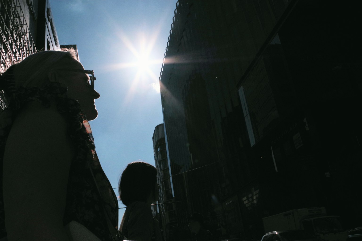 Silhouette di una persona in piedi in un paesaggio urbano sotto un sole brillante