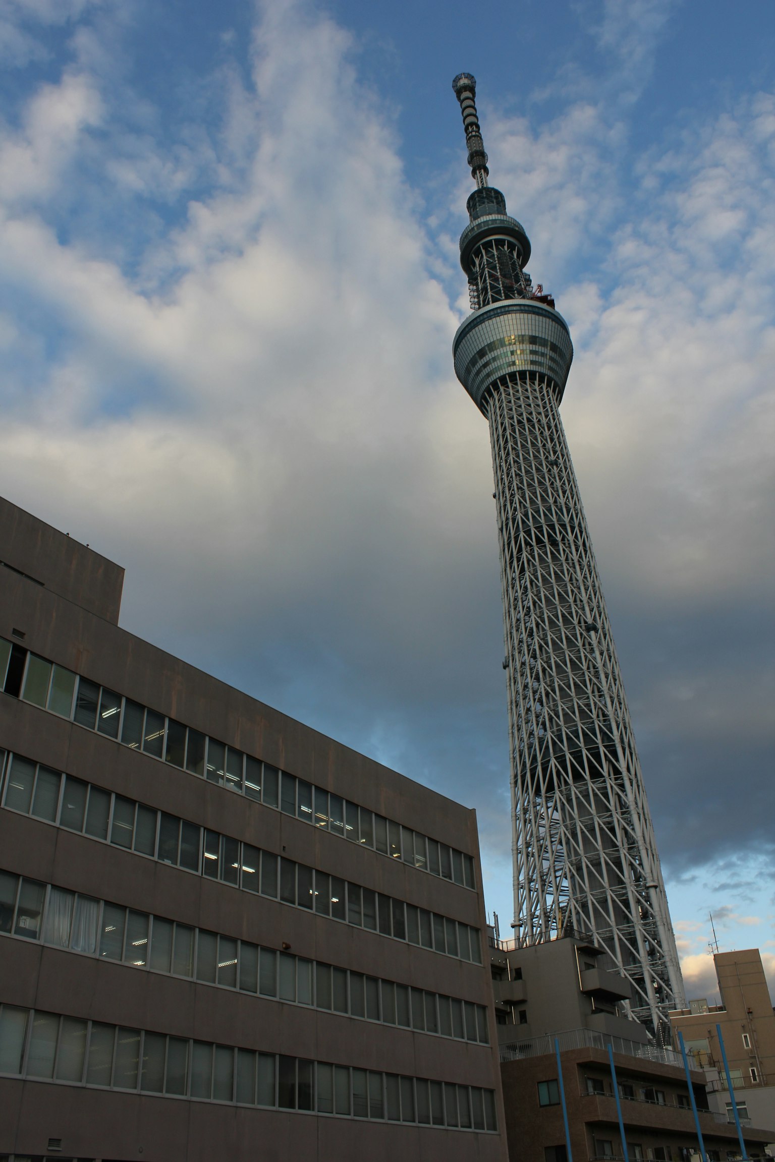 Tokyo Skytree menjulang di atas bangunan modern di bawah langit mendung
