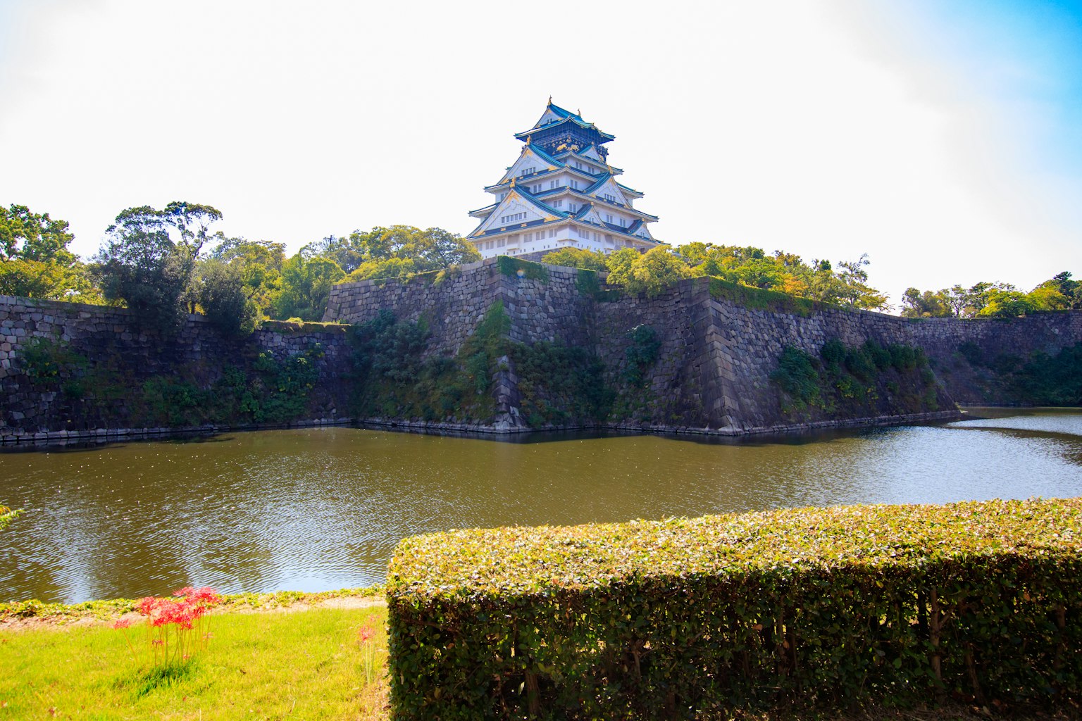 ทิวทัศน์ที่สวยงามของปราสาทญี่ปุ่นที่ล้อมรอบด้วยความเขียวขจีและบ่อน้ำสงบ