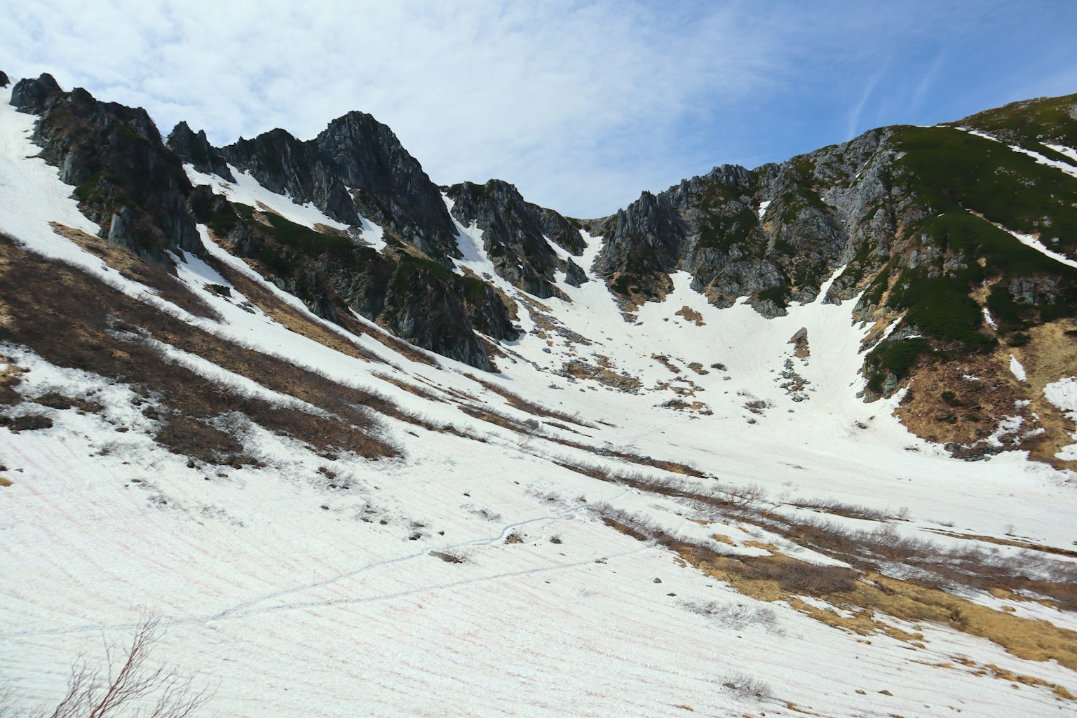 Pendiente de montaña cubierta de nieve con formaciones rocosas