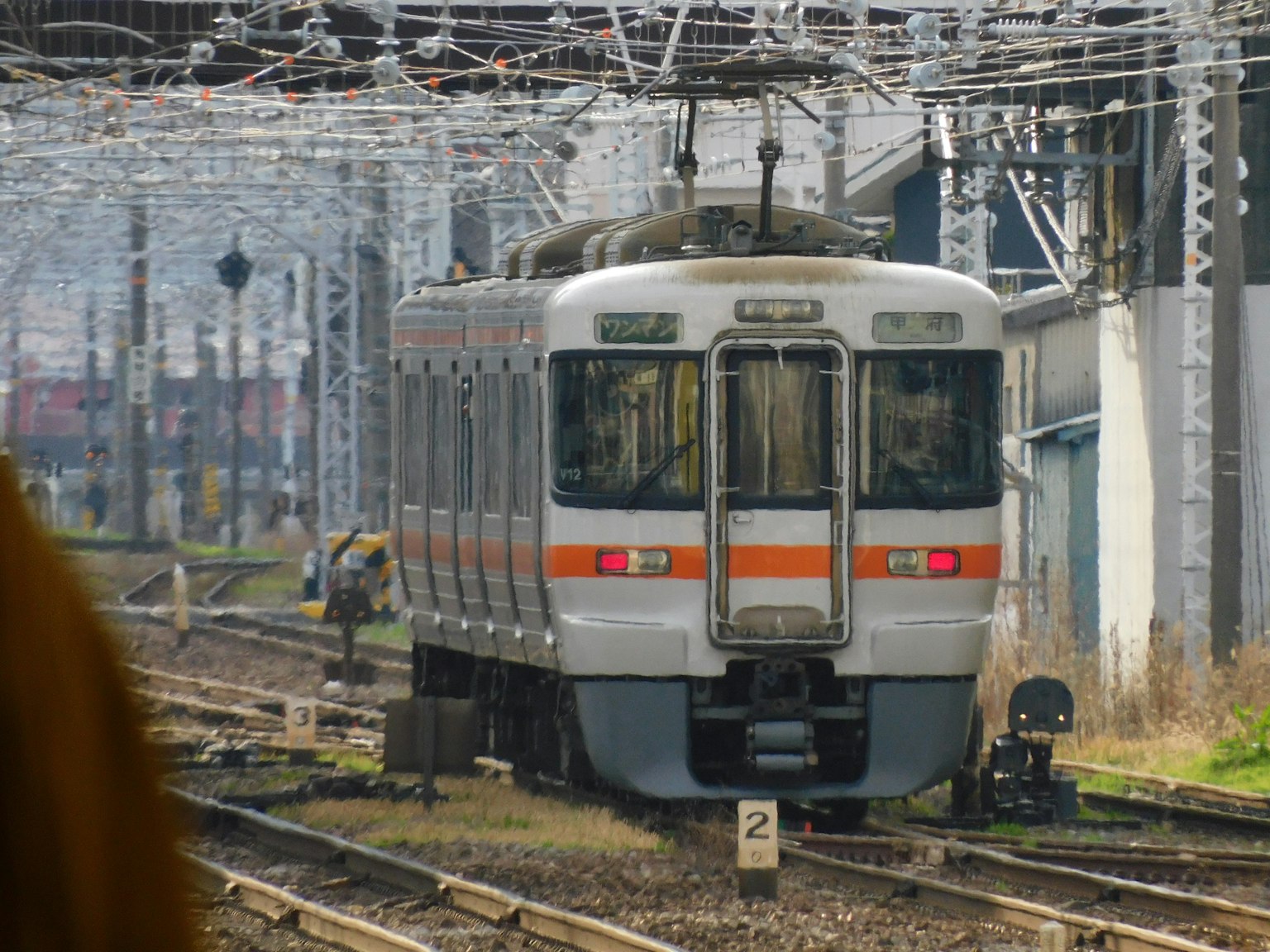 Train stopped on tracks with overhead wires crossing