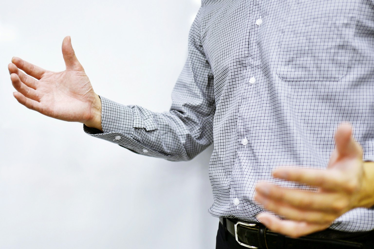 Un hombre con camisa a cuadros está gesticulando con las manos abiertas