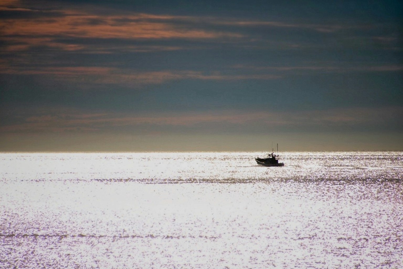 Una piccola barca che galleggia su un mare calmo con un bellissimo cielo al tramonto