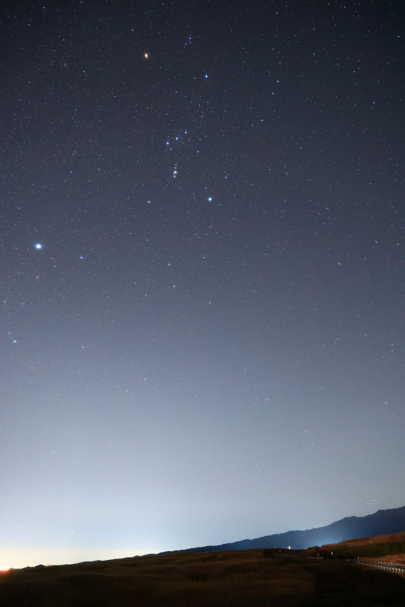 Vista del cielo nocturno con estrellas brillantes y la constelación de Orión