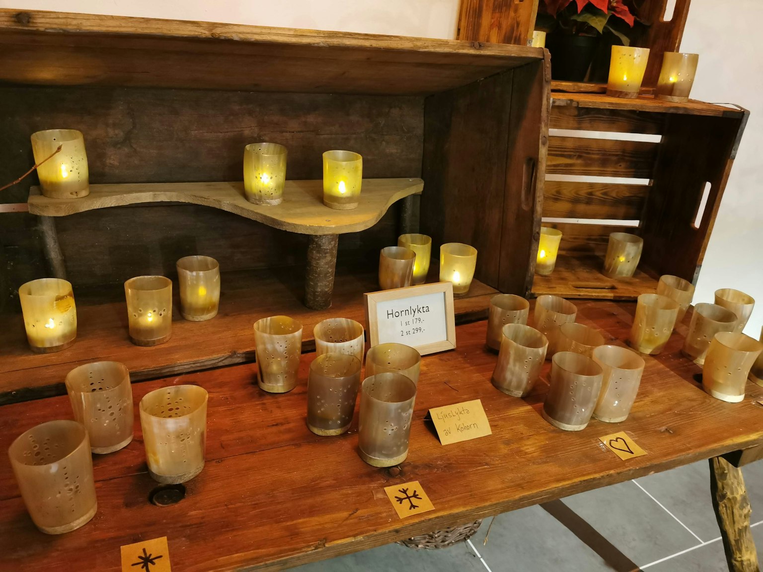 Display of various candle holders arranged on a wooden table with glowing candles