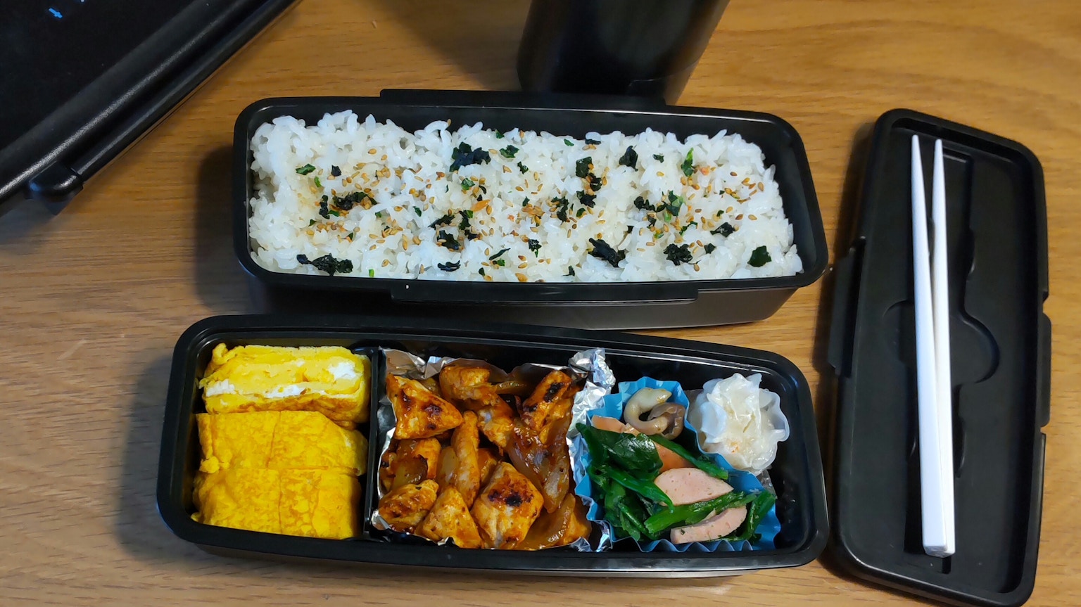 黒い弁当箱に盛られた寿司とおかずの盛り合わせ
