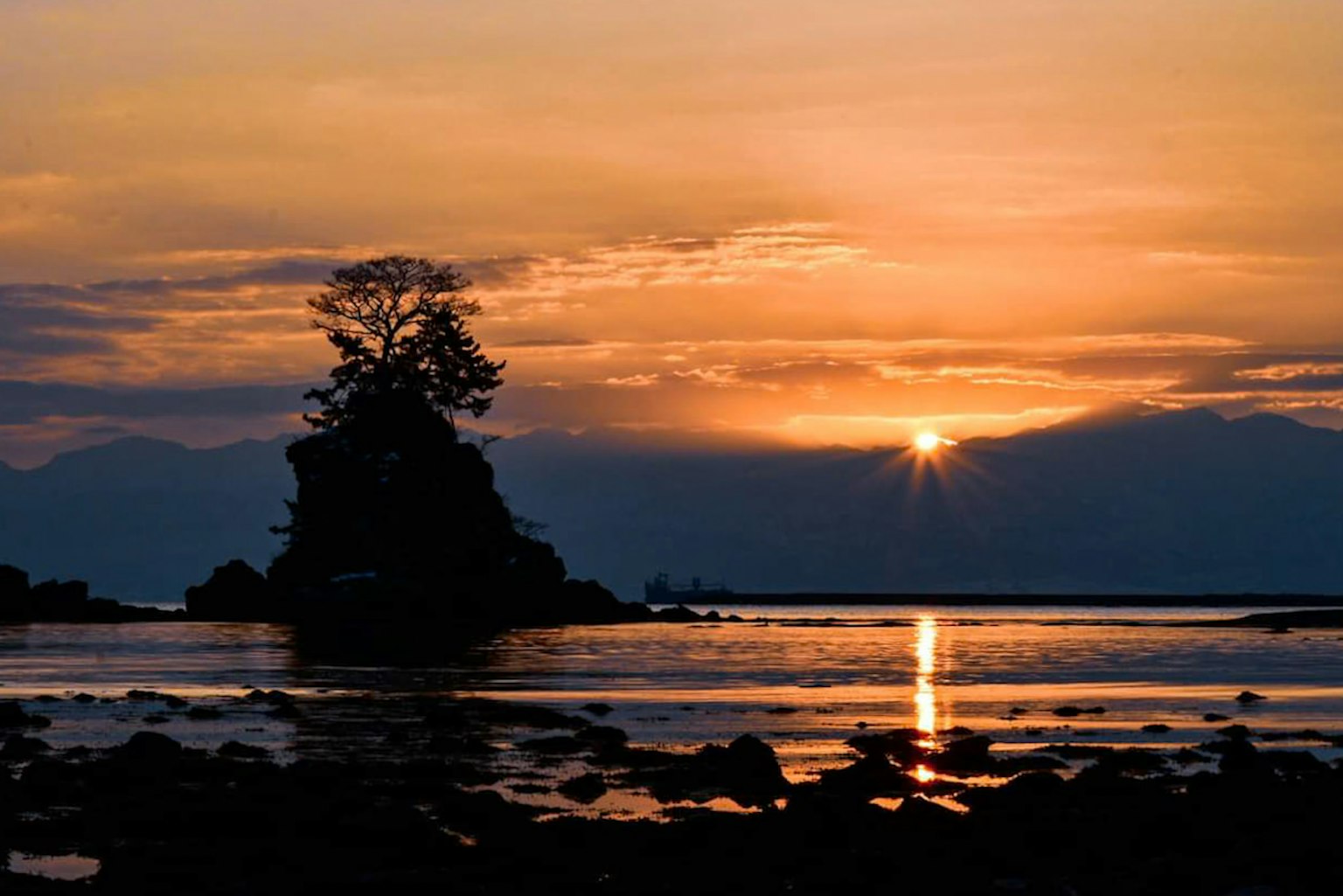 Silhouette pulau kecil dengan pohon di latar belakang matahari terbenam di laut