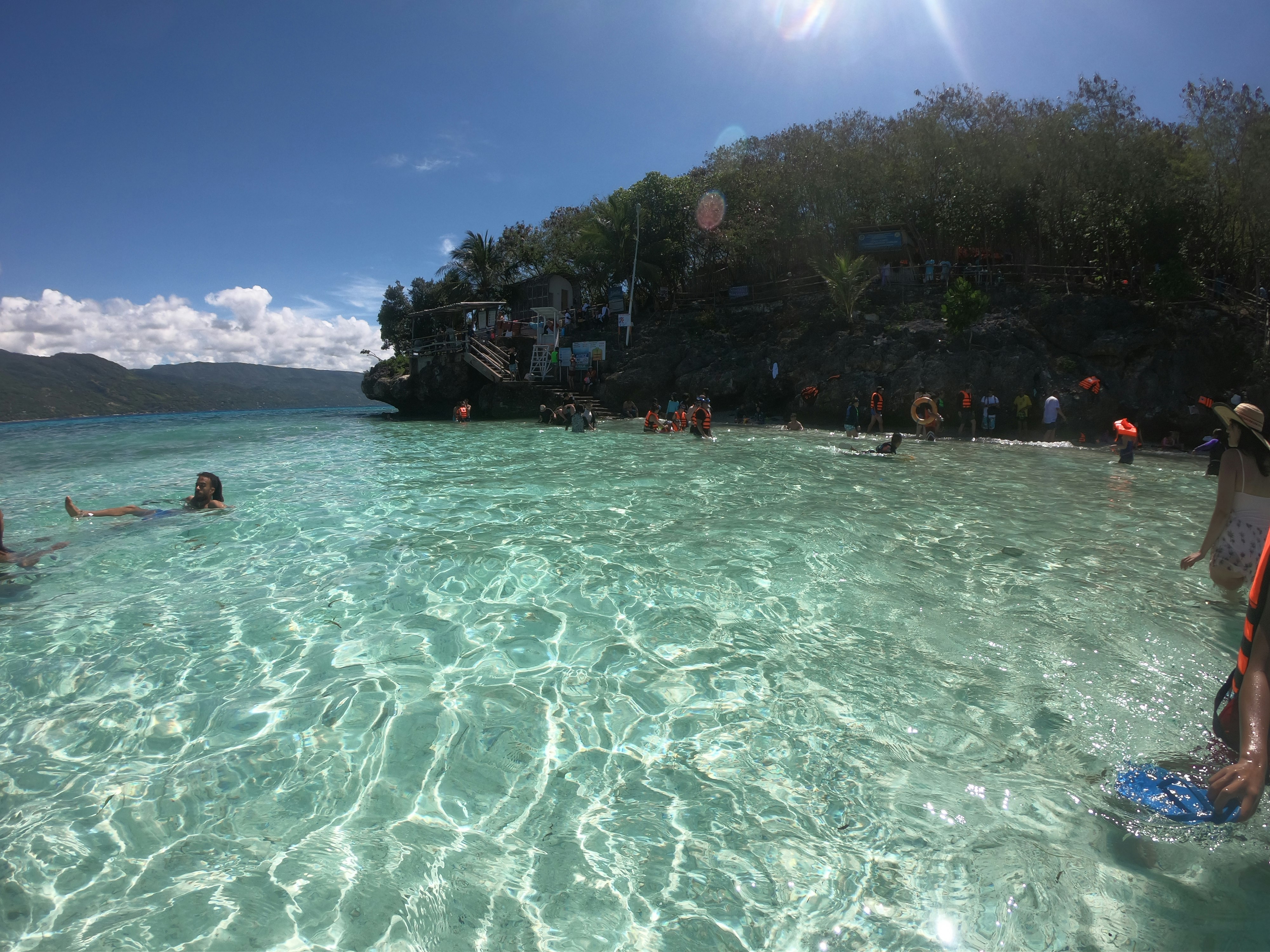 透明な海で泳ぐ人が見えるビーチの水面景色