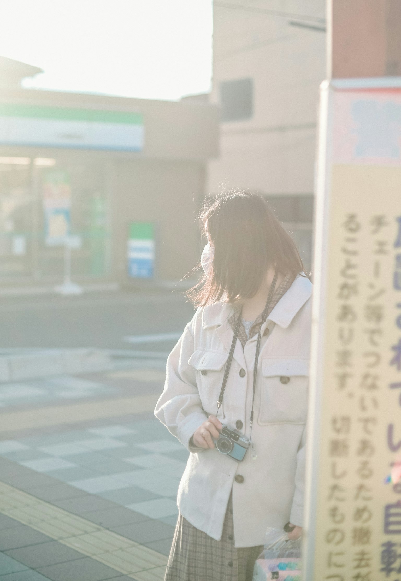 在柔和光線中站在標誌前的白色夾克女性