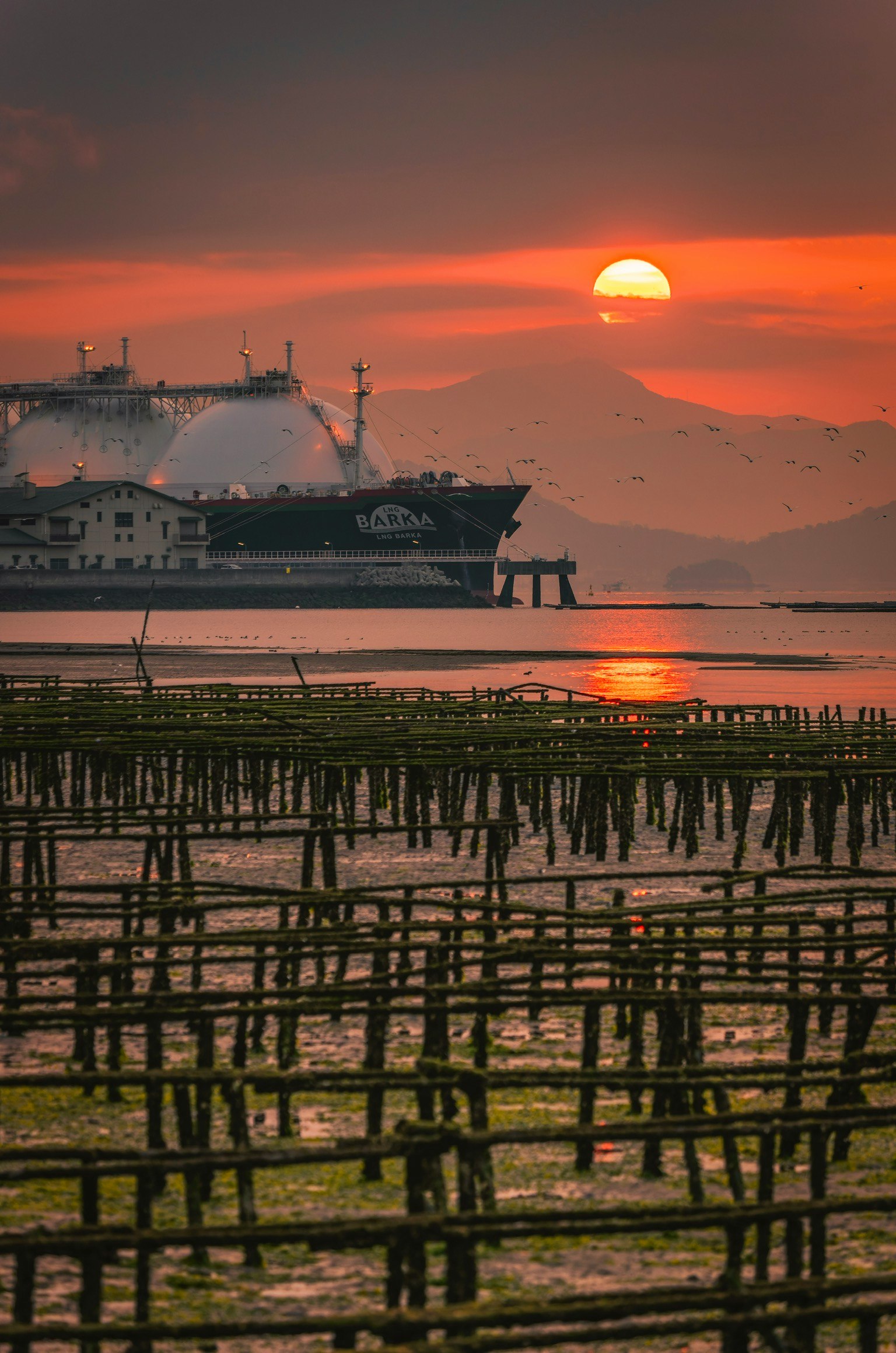 Eine schöne Landschaft mit einem Schiff und Wattflächen unter einem Sonnenuntergang