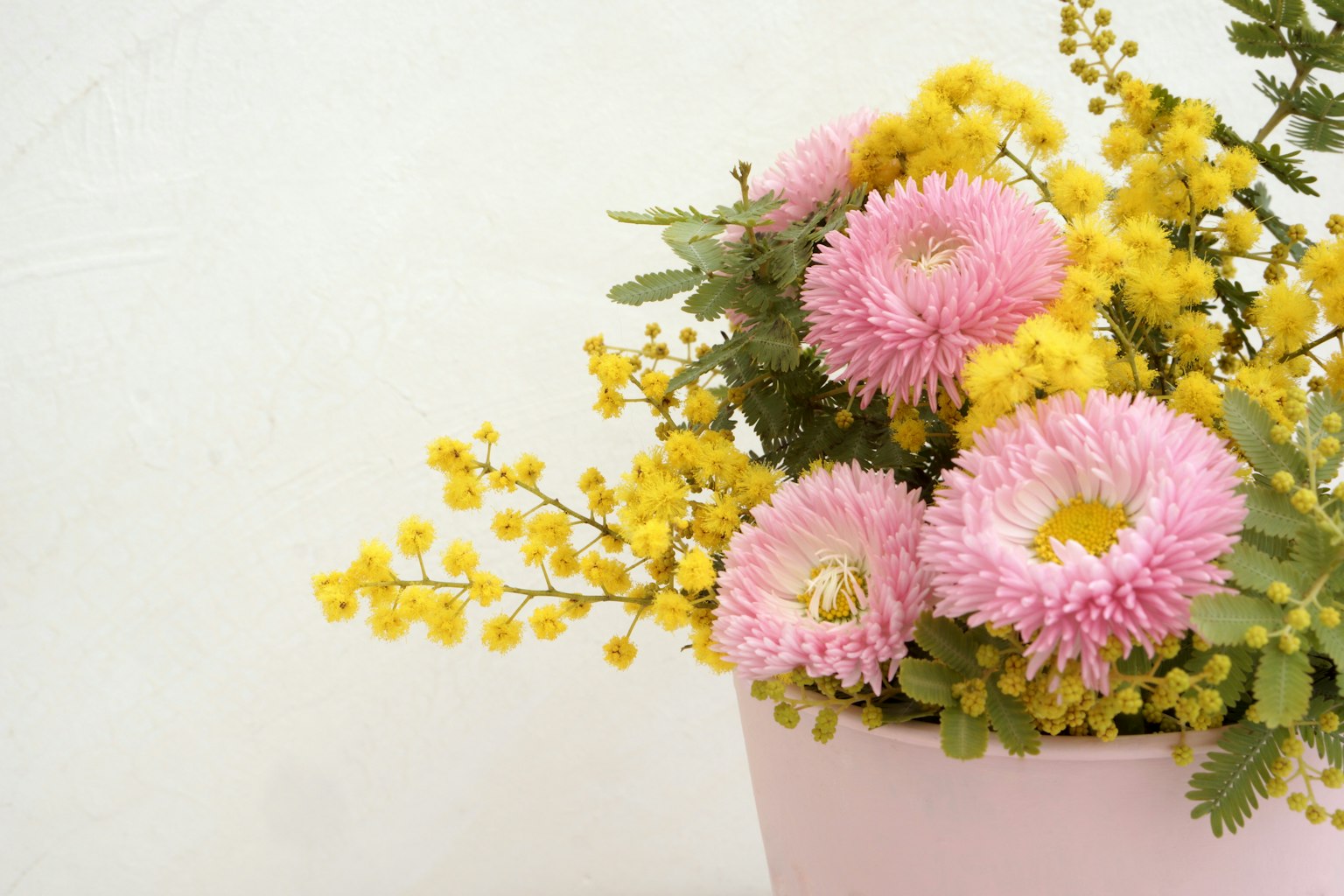 Bouquet de fleurs roses et jaunes dans un pot rose sur fond blanc