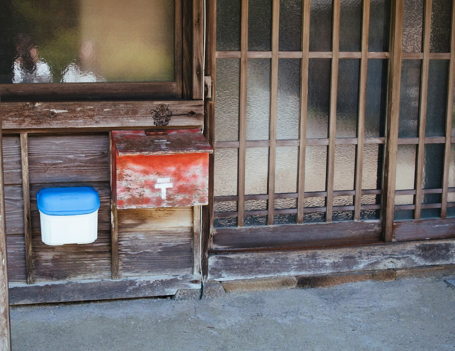 Teil eines alten japanischen Hauses mit einem Briefkasten und einem weißen Behälter