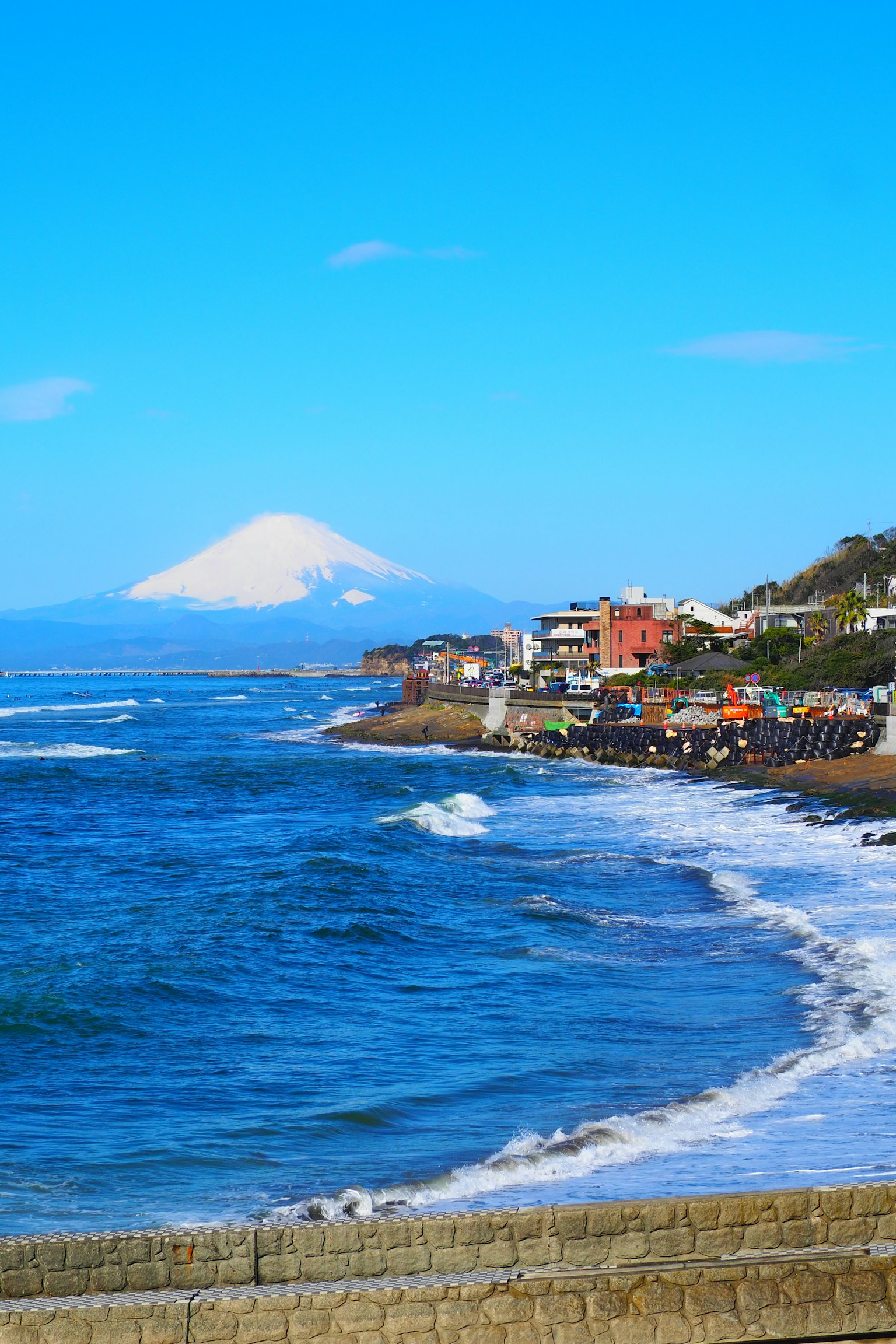 Vista costera con océano azul y el monte Fuji al fondo