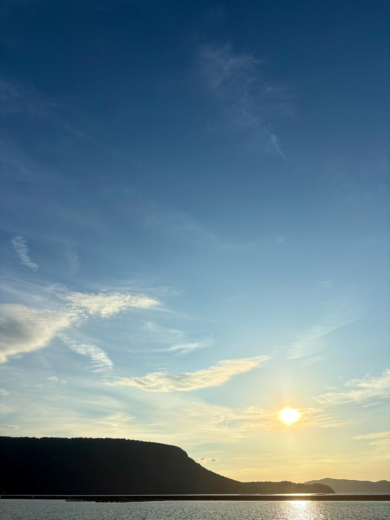 青空と雲が広がる夕暮れの風景 日が沈む山のシルエット