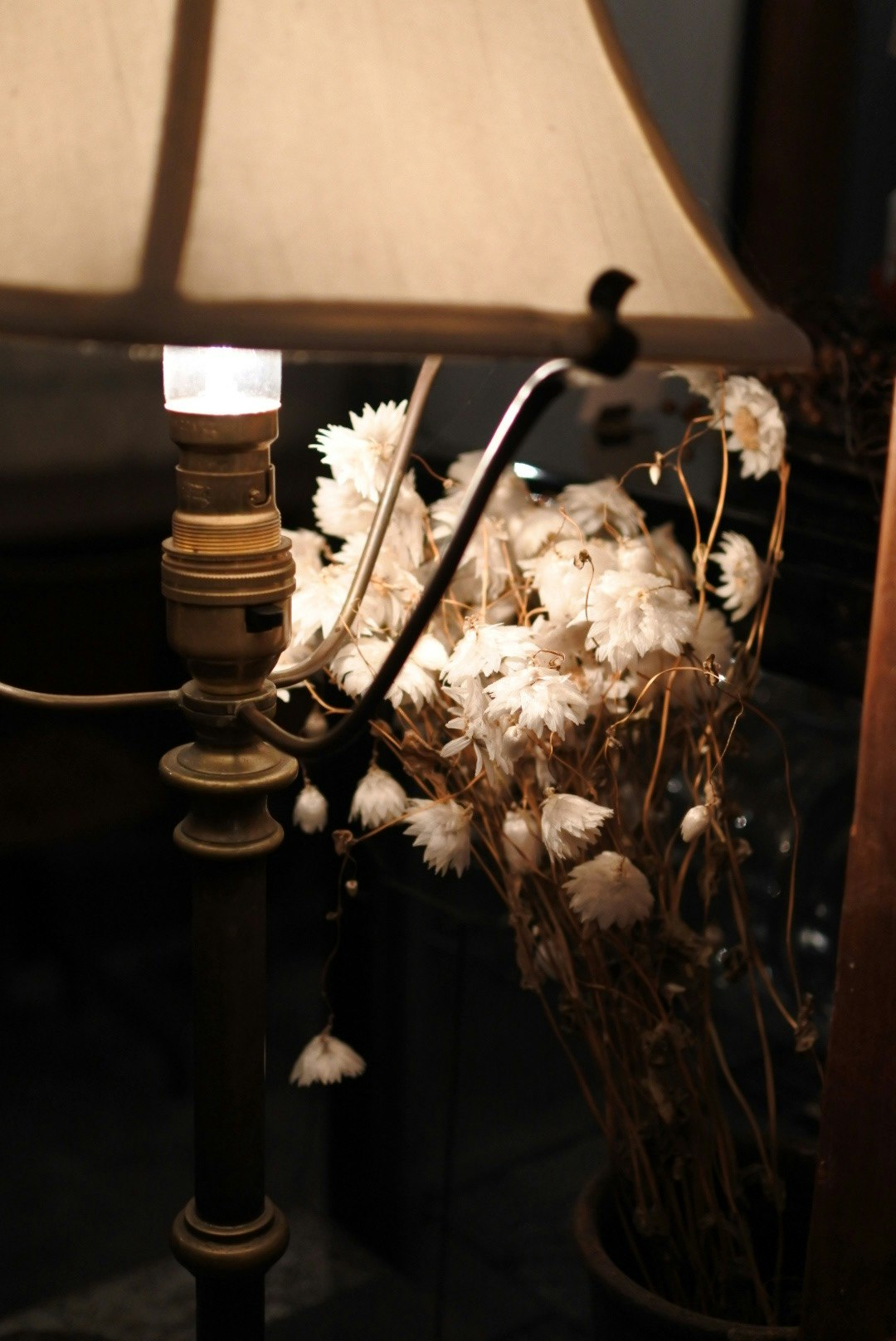 Un rincón interior tranquilo con una lámpara de estilo antiguo y flores secas