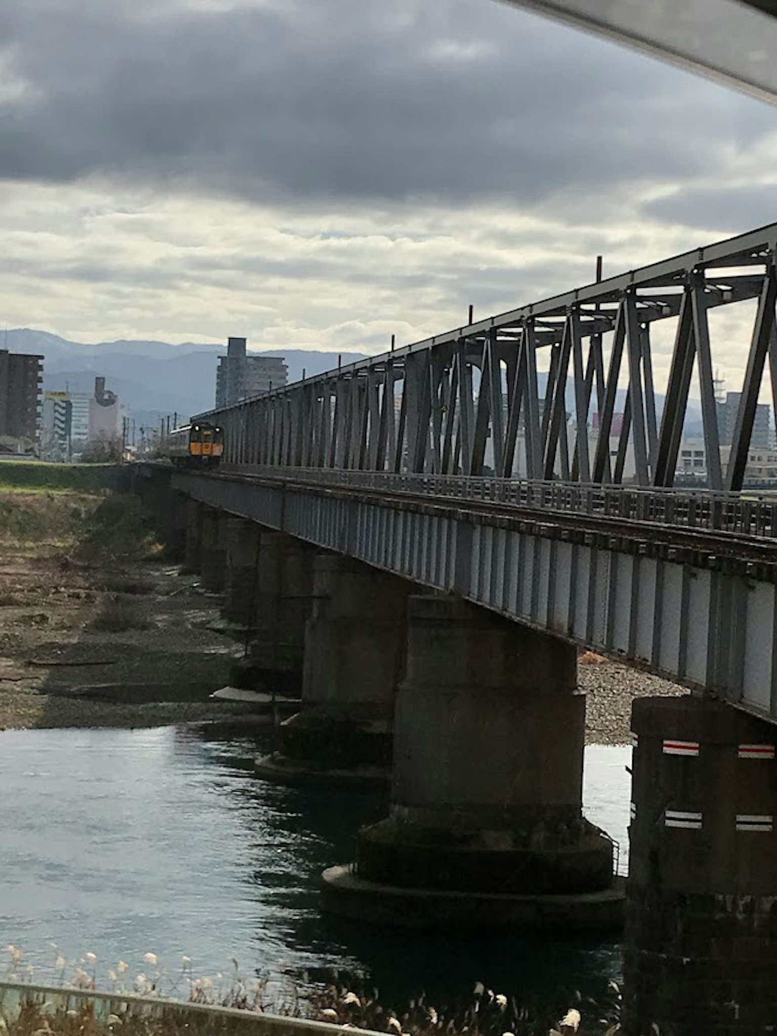 Un puente ferroviario cruza un río con edificios de la ciudad al fondo