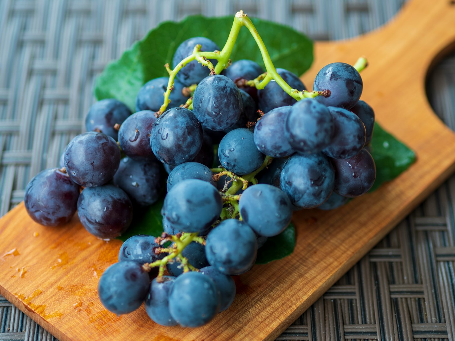 Fresh blue-purple grapes placed on a wooden cutting board