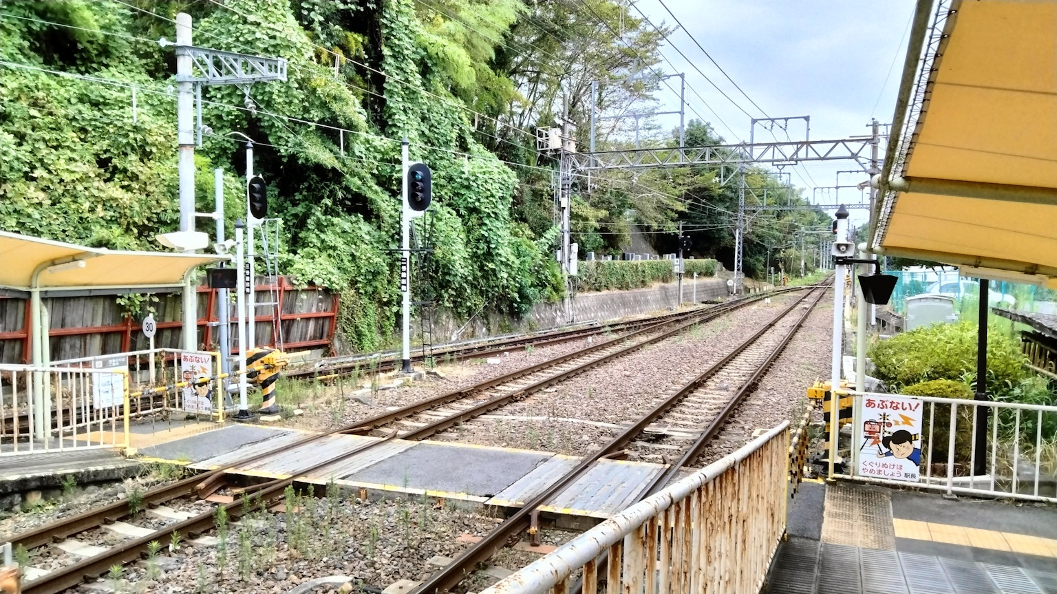 ฉากสถานีรถไฟที่เงียบสงบพร้อมสิ่งแวดล้อมสีเขียวรางรถไฟและสัญญาณ