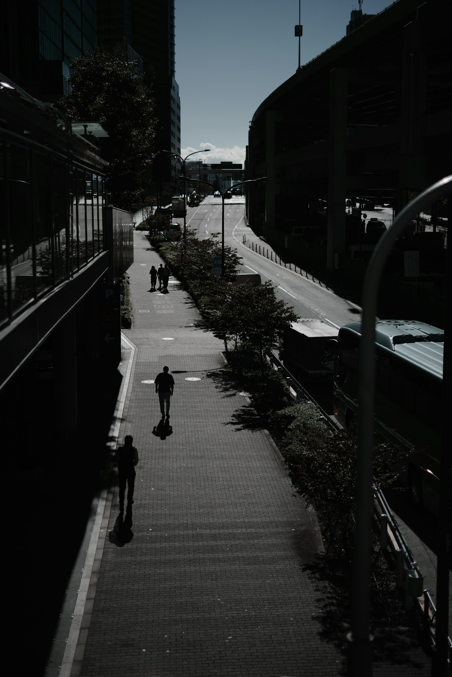 Scène urbaine avec des personnes marchant sur un chemin dans l'ombre