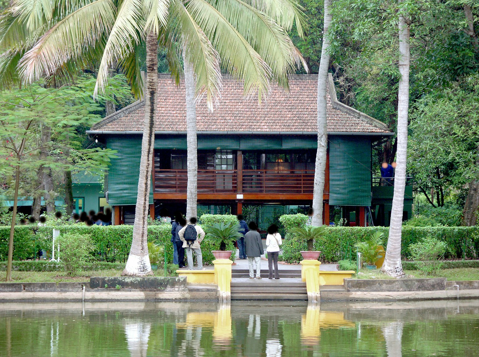 Casa in legno verde circondata da palme e stagno riflettente