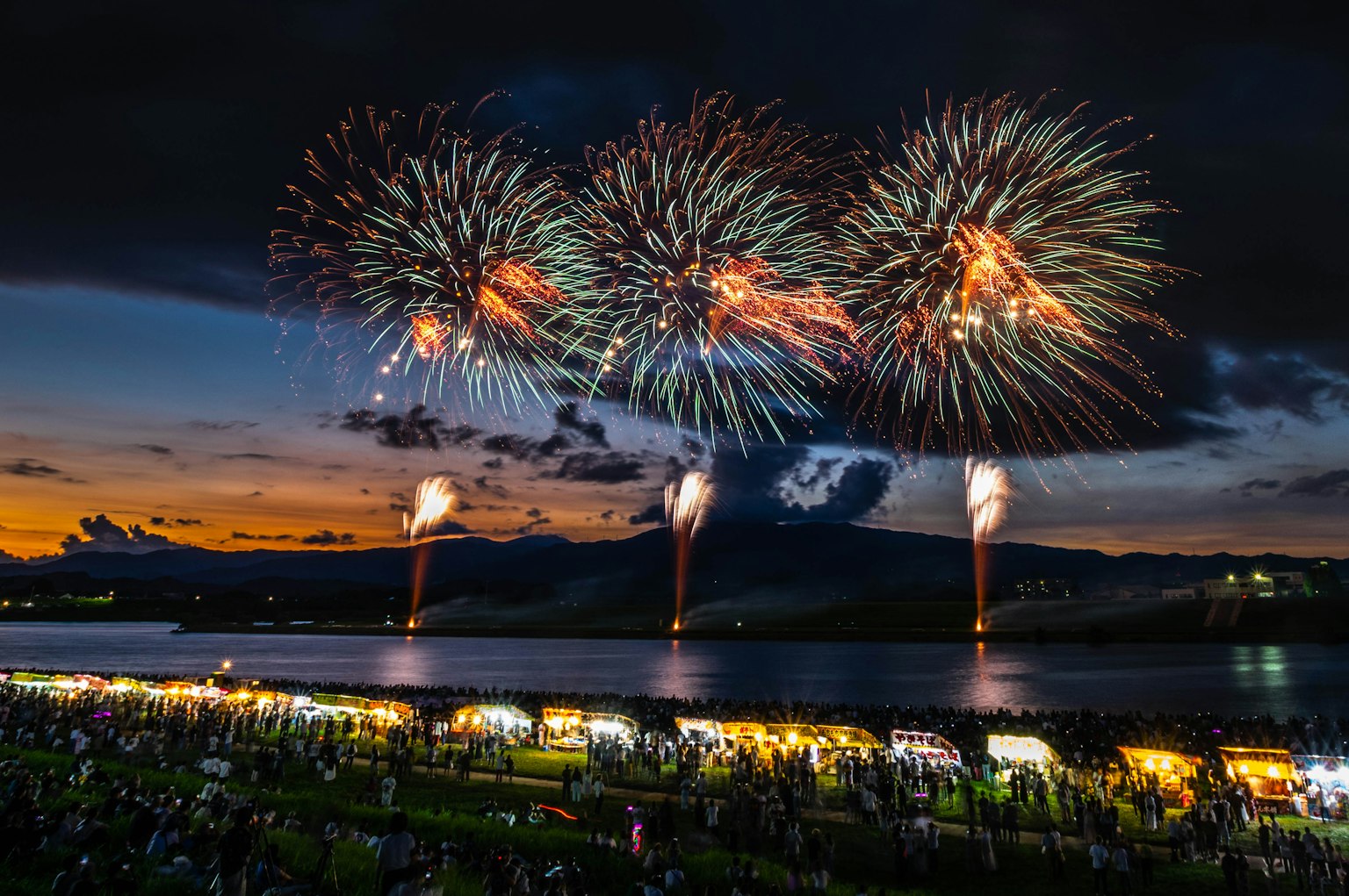 Spectacle de feux d'artifice colorés sur un lac au coucher du soleil