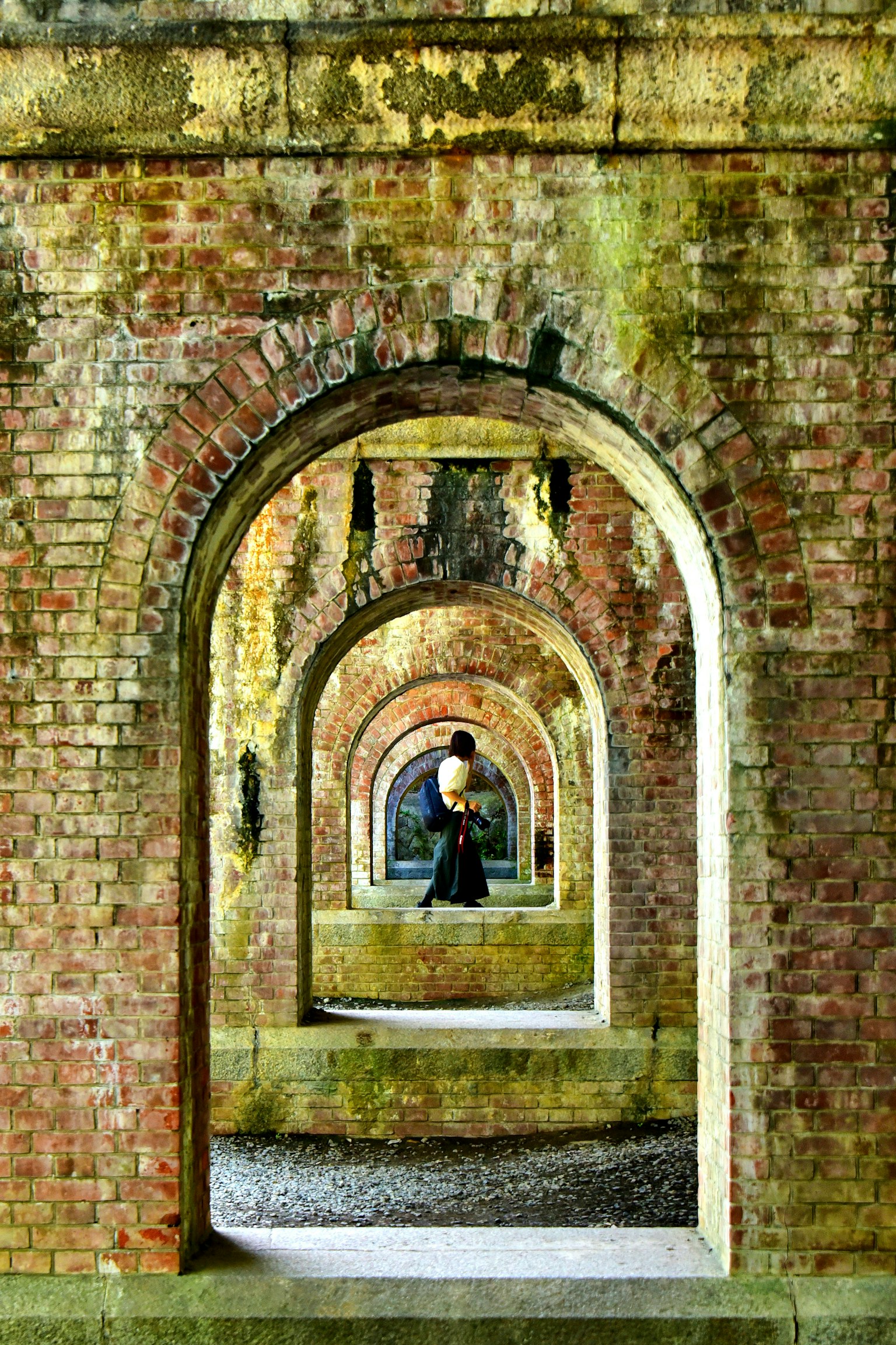Foto di una persona in piedi all'interno di una serie di archi in mattoni