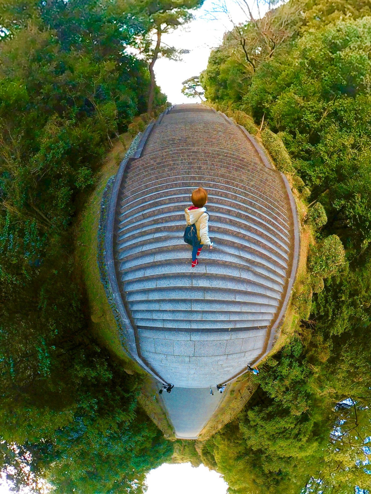 Eine Person, die eine gewundene Treppe umgeben von üppigem Grün hinaufgeht