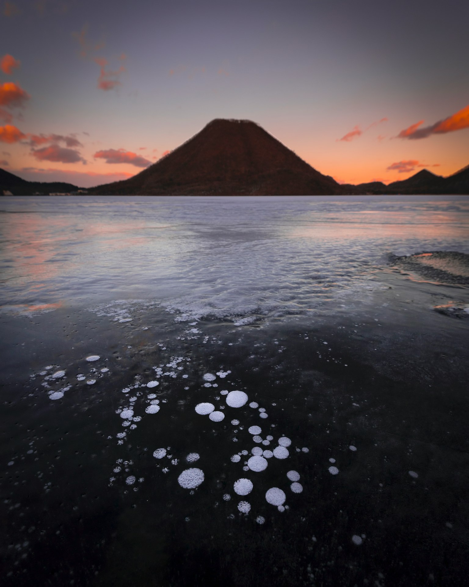 Paesaggio stupendo di un lago e di una montagna bolle che galleggiano sull'acqua calma al tramonto