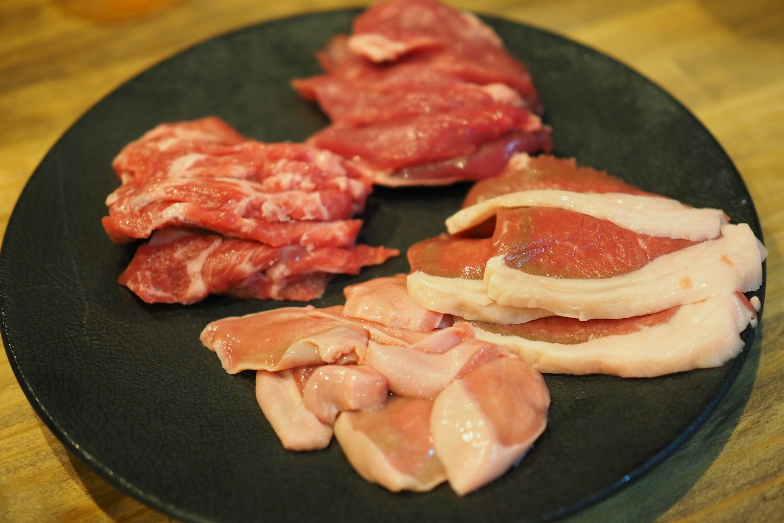 Un piatto con vari tipi di carne cruda disposti in modo elegante