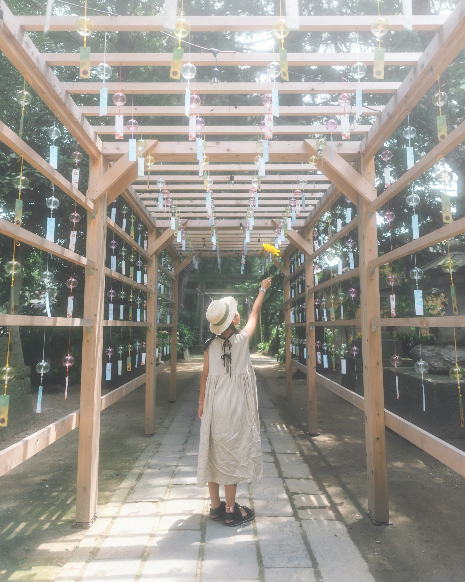 Una donna in piedi sotto un arco di legno che tiene un campanello a vento