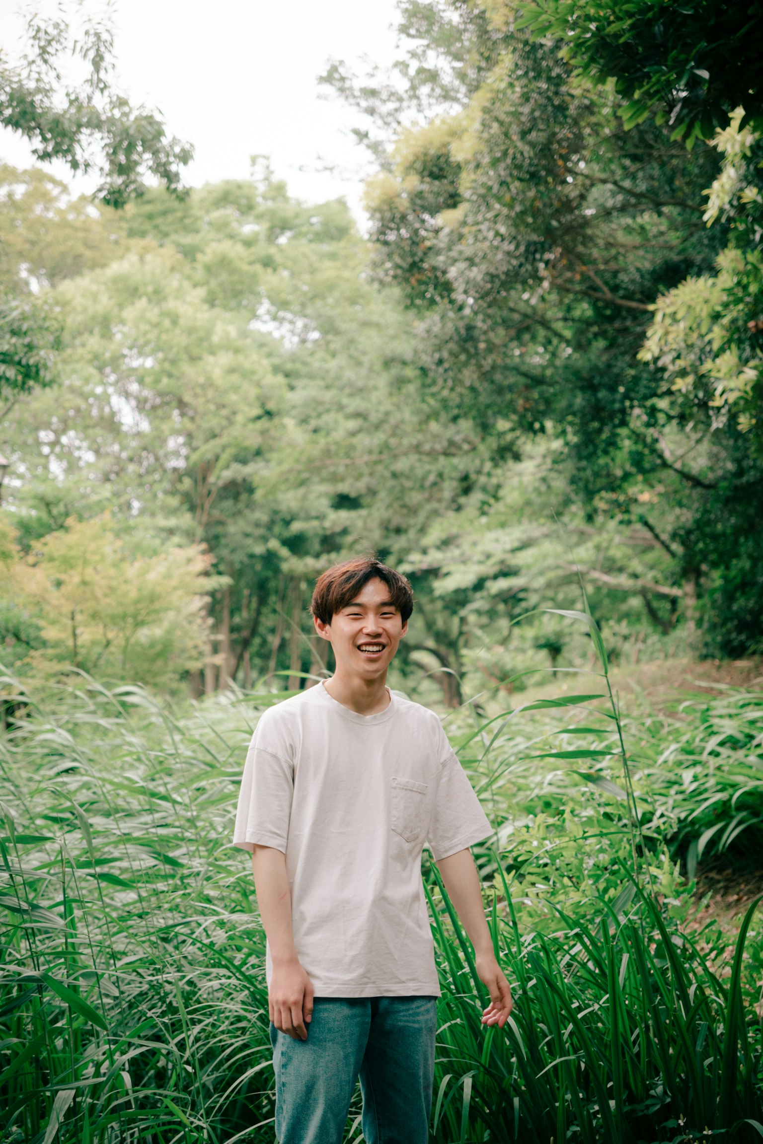 Jeune homme souriant dans un fond verdoyant