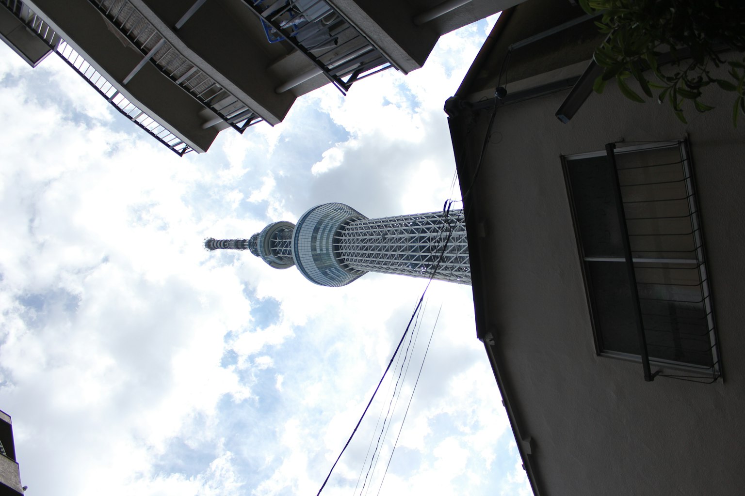 東京晴空塔在多雲的天空下從建築物間可見