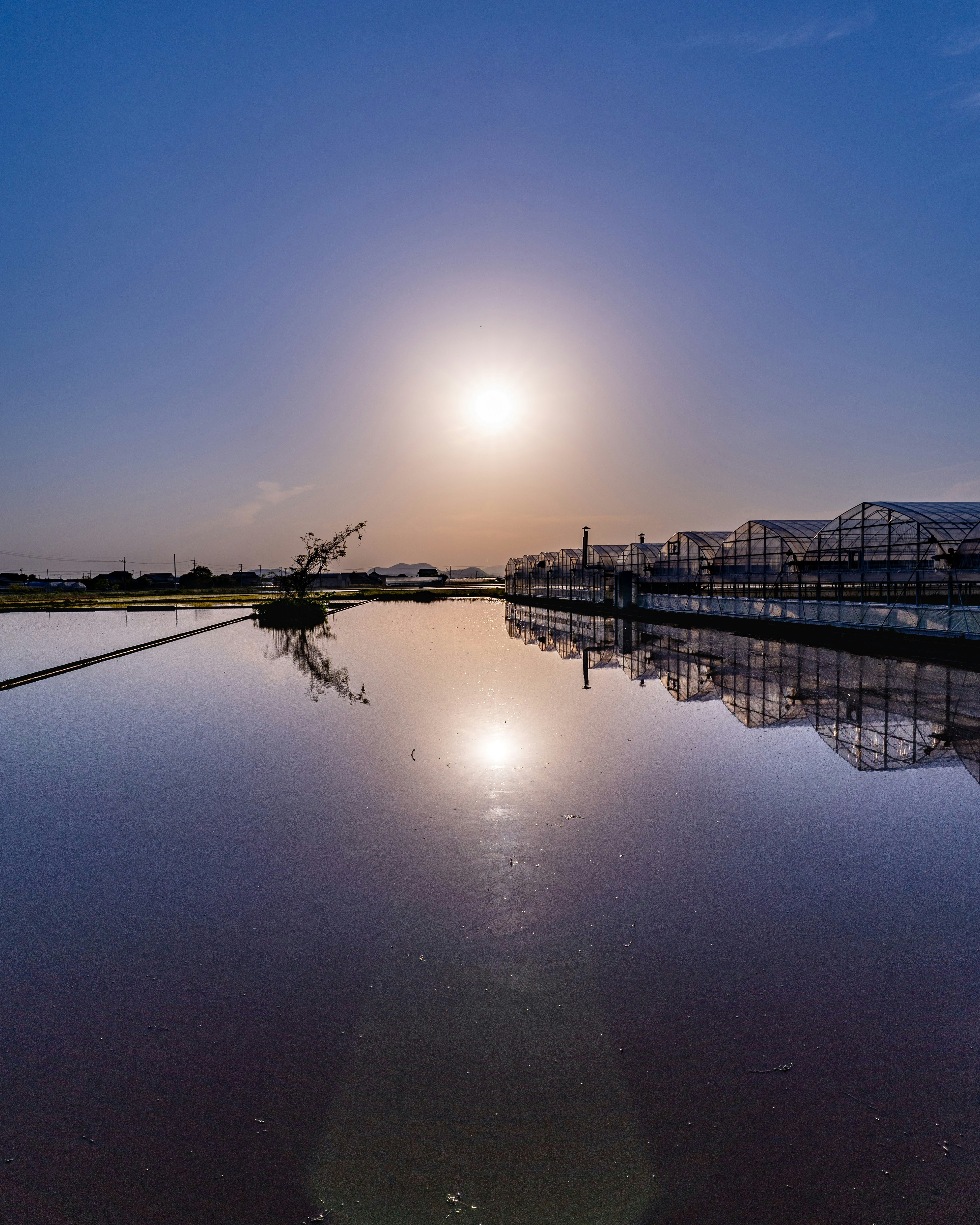夕暮れの水面に映る桟橋と工業施設のある風景