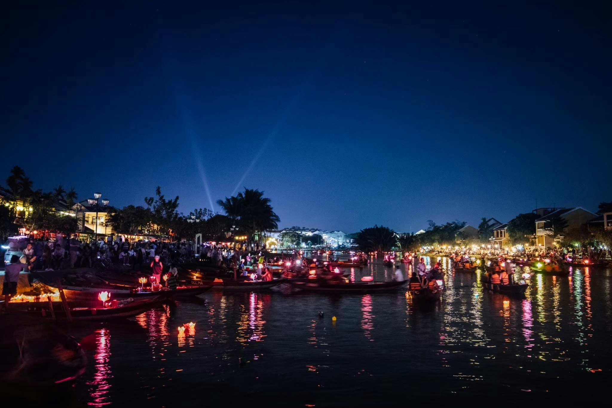 luci notturne lungo un fiume con persone presenti