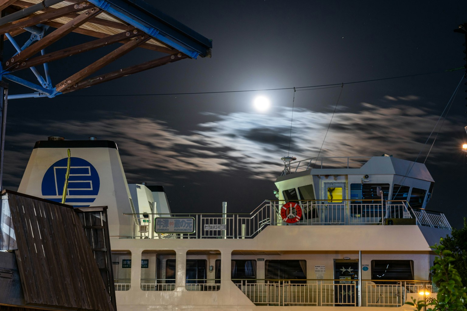 Escena nocturna de un barco con luna llena y nubes
