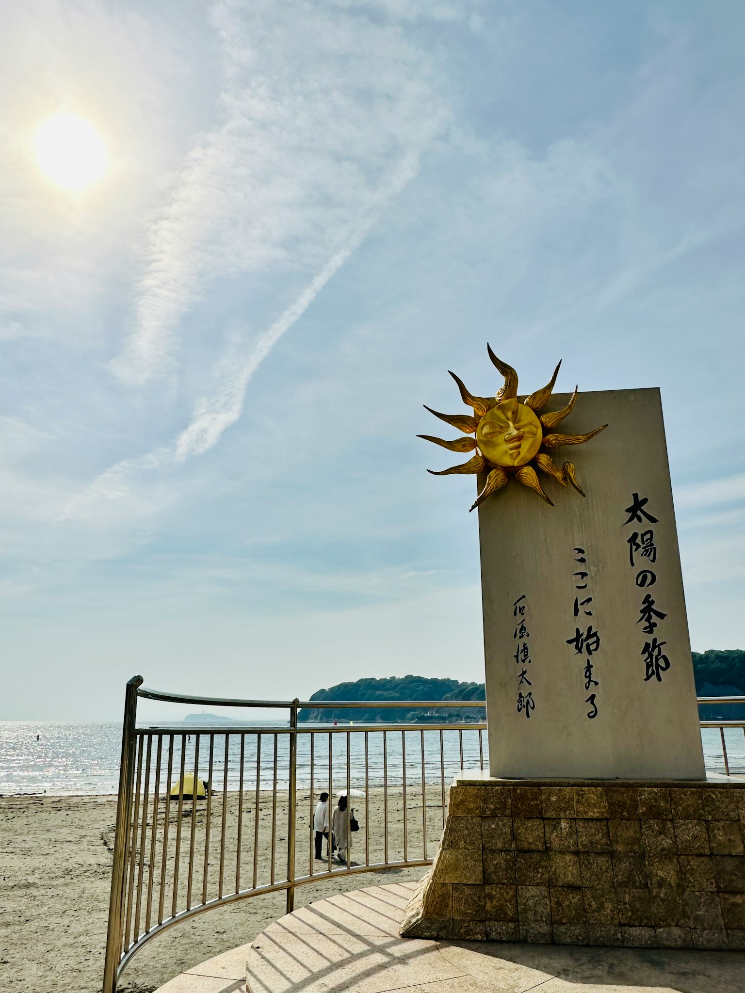 Sun sculpture with Japanese inscription at the beach clear sky and calm sea view