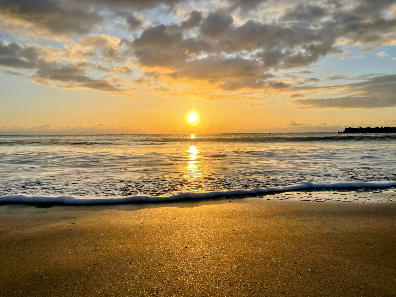 海滩场景，夕阳映在水面上